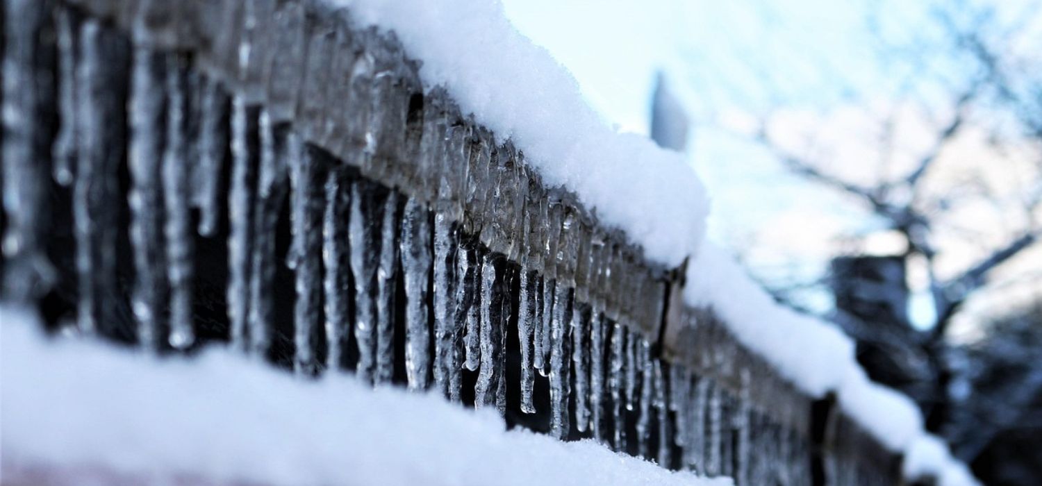 Sople lody zwisające z zaśnieżonego dachu