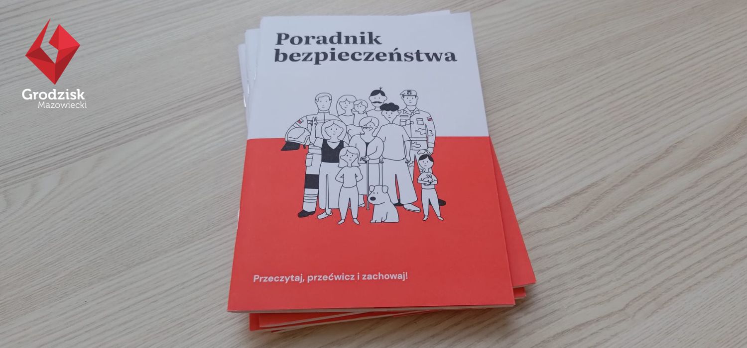 Na zdjęciu widać kilka egzemplarzy broszury „Poradnik bezpieczeństwa” ułożonych na jasnym, drewnianym stole. Na okładce znajduje się ilustracja grupy ludzi, a w lewym górnym rogu widoczne jest logo i napis „Grodzisk Mazowiecki”