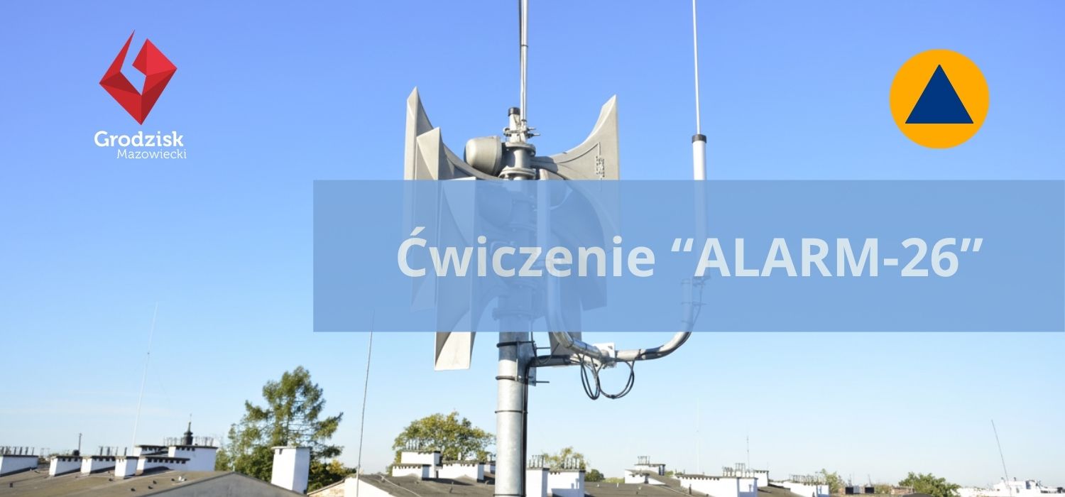 Na zdjęciu widać syrenę alarmową zamontowaną na maszcie na dachu budynku, na tle bezchmurnego nieba. Na środku grafiki umieszczono napis „Ćwiczenie ALARM-26”, a w lewym górnym rogu znajduje się logo Grodziska Mazowieckiego.